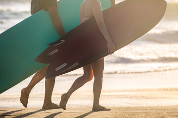 Fototapeta premium Surfers carrying surf boards walking the beach in Bali, Indonesia.