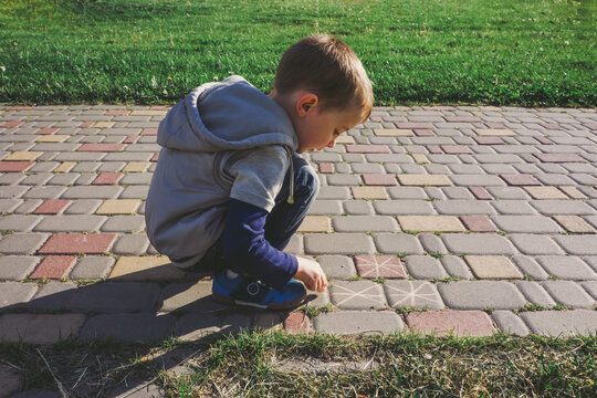 Boy using sidewalk chalk on a walkway