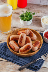 grilled sausages in a plate, sauces and beer nearby