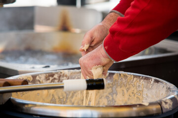 Close-up of a worker making beignets in an industrial kitchen.