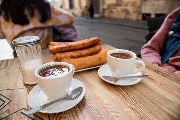 Churros and two cups of chocolate on the terrace table, ready to eat.