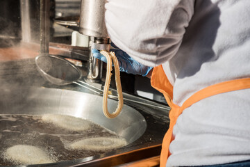 Detail of worker making churros on the industrial metal kitchen.