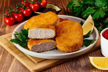 chicken cutlet on a plate. vegetables and herbs. wooden table