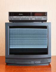 Obraz premium Old vintage TV with noise on the screen, VCR on the background of the wallpaper.East Germany GDR.