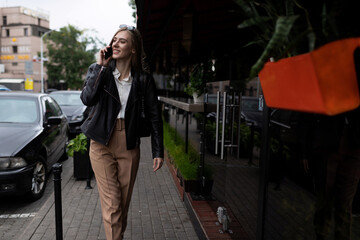 Fototapeta premium successful young adult female student walking around the city and talking on the phone