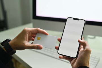 Close up view of man holding using mobile phone and credit cad for online banking transaction,...