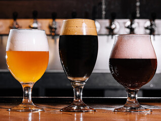 three types of craft beer in glasses on table in pub interior