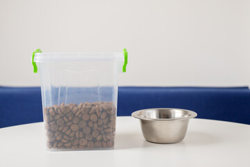 pet food, dosing of dog feed, packaging and storage of cat nutrition, dry food in a container and a pet bowl on the table