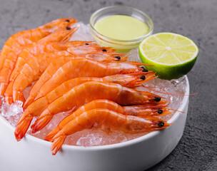 A group of tiger shrimp on a bowl of ice with lime