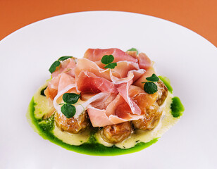 Salad with prosciutto and artichokes on a white plate