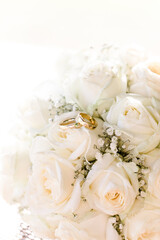 goldene Eheringe auf weißen Rosen bei Hochzeit