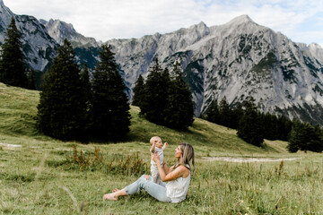 Mutter und kleines Kind am Berg sitzend auf einer grünen Wiese