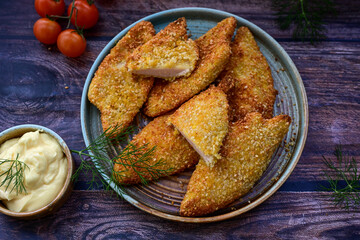 
 Crispy oven baked  chicken breast with sesame seeds and ketchup. Breaded chicken fillets  with chilly peppers and fresh basi on wooden rustic background
