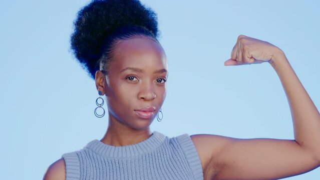 Strong, muscle and face of a black woman with biceps isolated on a blue background in a studio. Serious, confident and portrait of an African girl with power, empowerment and showing gym progress