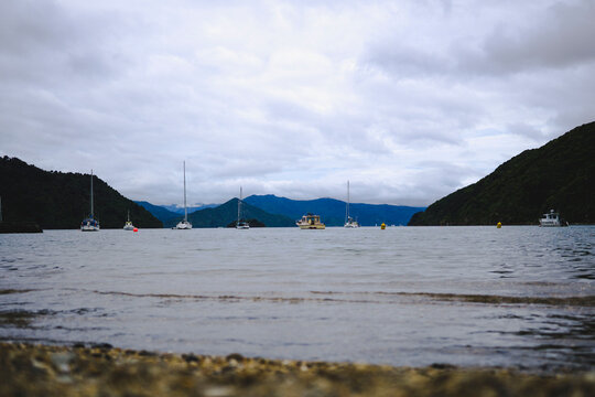 Boats on river by mountains against cloudy sky