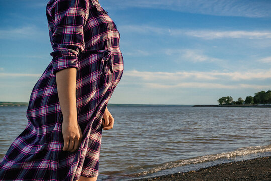 Midsection of pregnant woman standing on shore against sky