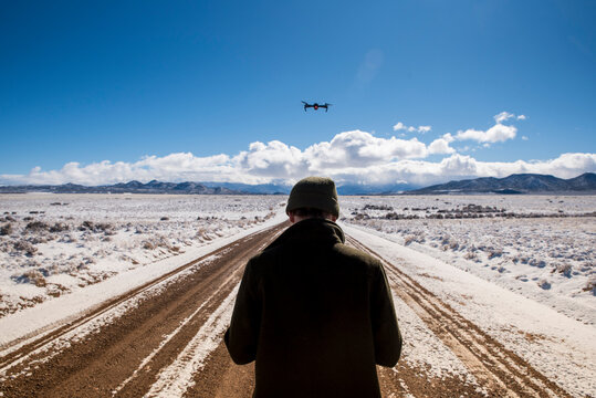 Rear view of man flying drone against sky at desert during winter