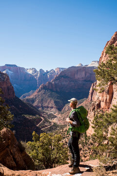 Full length of hiker with backpack looking at rock formations while standing on desert against clear sky