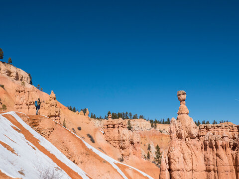 Mid distance view of hiker on rock formation against clear blue sky at desert