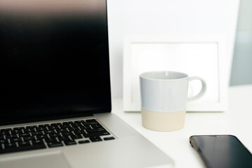Close-up of coffee cup by laptop computer on desk