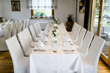 Fototapeta na wymiar Brauttisch bei Hochzeitsfeier in Restaurant mit weißer Tischdecke und Stuhlhussen