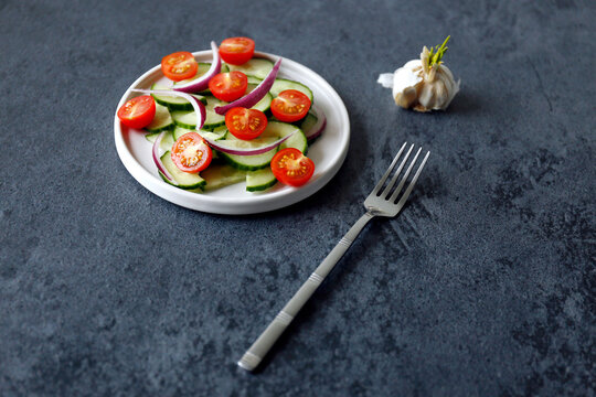 High angle view of salad served in plate with garlic bulb and fork on table