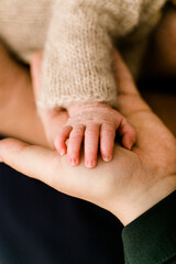Winzige Babyhand auf Hand der Mutter