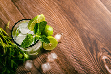 Mojito, cocktail decorated with lemon and peppermint on a wooden table. No straw.