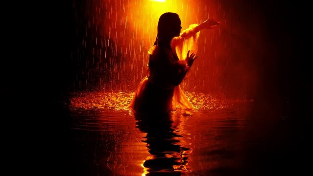 Silhouette of a beautiful woman in the rain in aqua studio