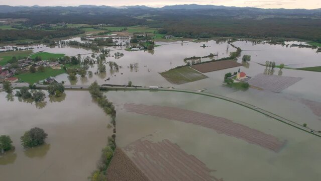 AERIAL: Large agricultural area submerged under muddy floodwater near the village. Raised river water approached residential houses after spilling over riverbanks. Autumn flood after heavy rainfall.