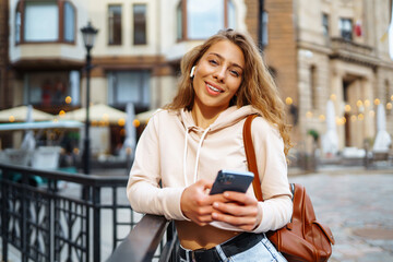 Photo of a woman using smart phone. Beautiful woman texting on the street. Beautiful woman spending time in the city. 