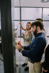 Young business people sticking and writing on notes over glass wall