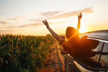 Happy woman outstretches her arms while sticking out the car window. Lifestyle, travel, tourism,...