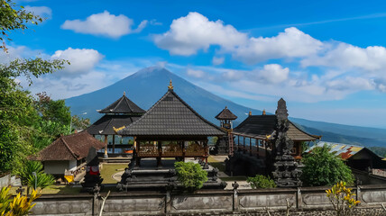 Fototapeta na wymiar Balinese traditional building with temple or also called pura where Hindus pray and give offerings with Mount Agung background with blue sky and clouds