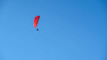 Paragliding in the sky. Paraglider flying over the cliff and mountain with blue sky in bright sunny day. Paragliding in Pandawa Beach, Bali, Indonesia. Extreme sport.
