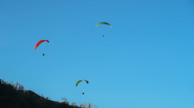 Paragliding in the sky. Paraglider flying over the cliff and mountain with blue sky in bright sunny day. Paragliding in Pandawa Beach, Bali, Indonesia. Extreme sport.