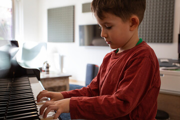 Beautiful young boy learning to play piano