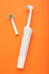 Modern electric toothbrush on orange background. Controlled tool for daily oral care.