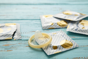 Opened condom and condom in pack on blue background. A condom use to reduce the probability of...