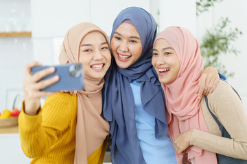 Group of happy cheerful Asian muslim women taking a selfie photography or making video live steaming on a social network by using smartphone.