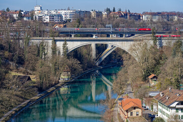 Bridges over Aare River with bus and train crossing at Swiss City of Bern on a sunny winter day....