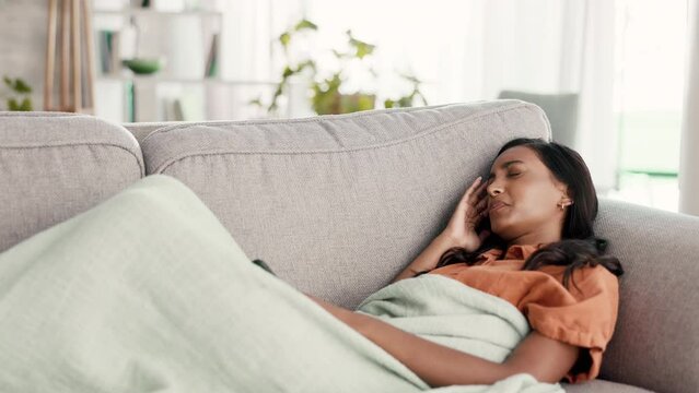 Woman with headache, lying on couch and sick, illness and pain, relax at home with migraine and problem. Indian female with head cold, smartphone and wifi, stress with fatigue and physically ill