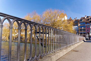 Close-up of railing of bridge over Aare River with whit castle in the background at Swiss City of Thun on a sunny winter day. Photo taken February 21st, 2023, Thun, Switzerland.