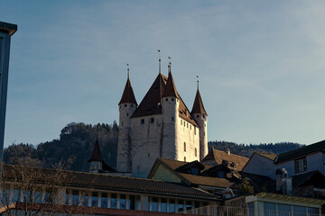 Fototapeta na wymiar Old town of City of Thun with white castle on a hill in the background on a sunny winter day. Photo taken February 21st, 2023, Thun, Switzerland.