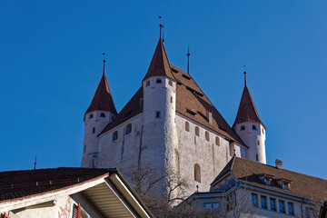 Fototapeta premium Old town of City of Thun with white castle on a hill in the background on a sunny winter day. Photo taken February 21st, 2023, Thun, Switzerland.