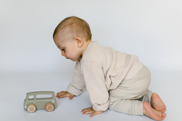 Kleiner Junge krabbelt und spielt mit Holzauto in naturfarben © freudelachenliebe