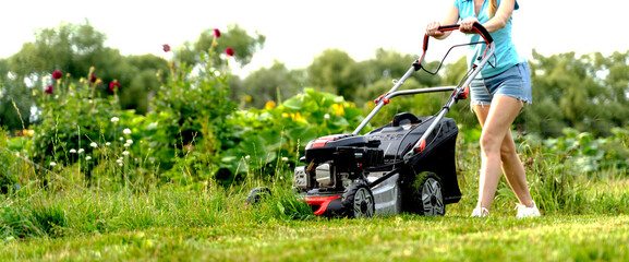 a girl mows the lawn with a lawn mower - obrazy, fototapety, plakaty