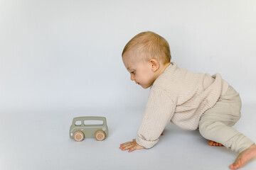 Kleiner Junge krabbelt und spielt mit Holzauto in naturfarben © freudelachenliebe