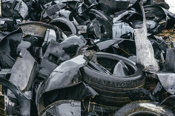 A dump of broken rusted cars, their parts and tires