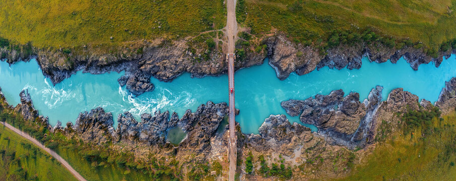 Red car on suspension Oroktoysky bridge over Katun river in valley of Altai Mountains, aerial top view. Travel landmark in Chemal Siberia, Russia